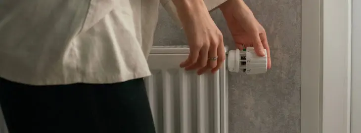 Homeowner adjusting a thermostatic radiator valve to control heating