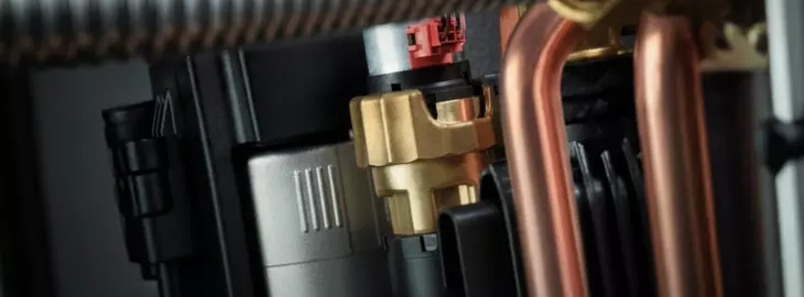 Close-up of copper pipework and diverter valve inside a modern combi boiler.