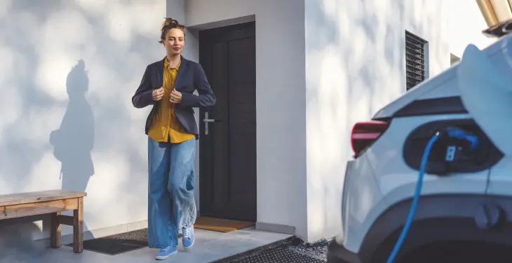 Homeowner walking past an electric car charging on a driveway using a domestic EV charger