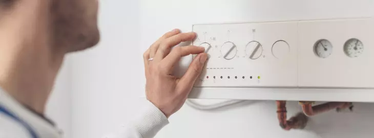 Homeowner checking boiler pressure gauge and control panel for low system pressure.