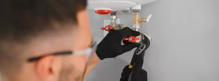 Engineer tightening boiler valves to ensure the filling loop is fully closed