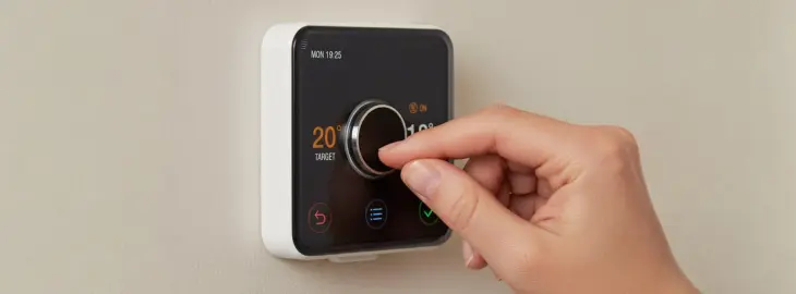 Hand adjusting a smart thermostat dial during a boiler system reset