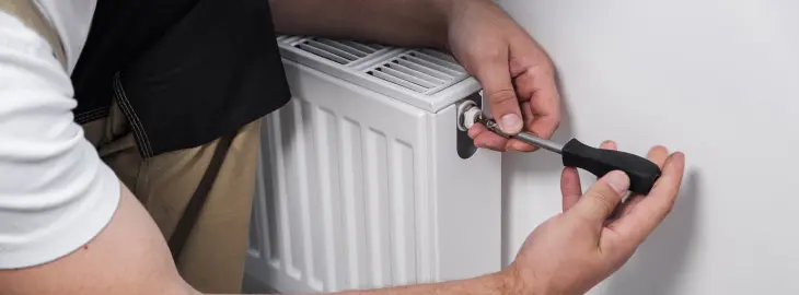 Engineer using a radiator valve to release water and reduce boiler pressure.