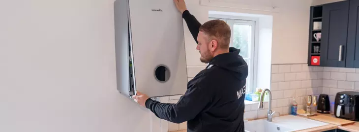 Heating engineer installing a new boiler in a modern kitchen