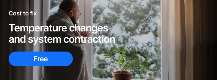 Person wrapped in a blanket looking out at snowy weather, illustrating how cold temperatures can affect boiler pressure.