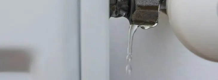 Water dripping from a radiator gland nut or pipe joint indicating a heating system leak