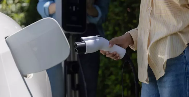 Person plugging an electric vehicle into a home charging point using a Type 2 EV charging cable